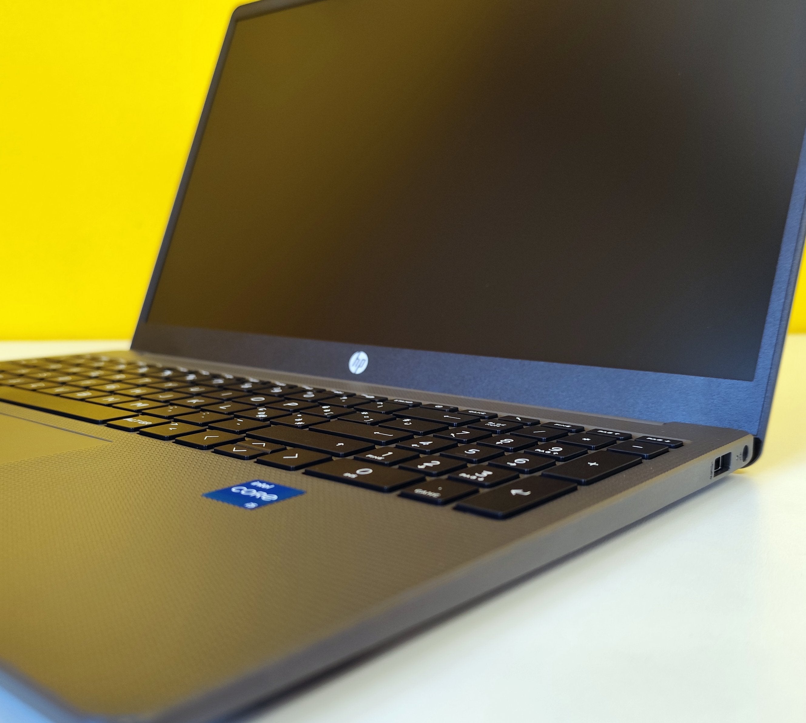Notebook HP 250 G10 con adesivo Intel Core i5 visibile, tastiera estesa e design elegante su sfondo giallo. Notebook HP 250 G10 con adesivo Intel Core i5 visibile, tastiera estesa e design elegante su sfondo giallo.